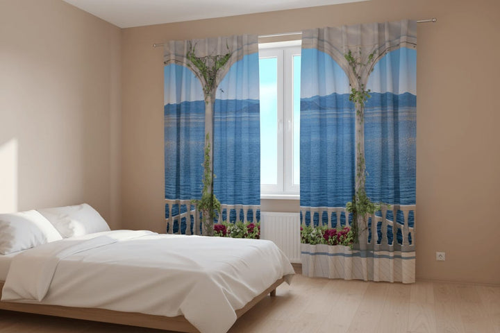 Gaišas guļamistabas interjers ar koka grīdu un gaišu gultu. Uz loga uzstādīti fotoaizkari ar optisko ilūziju, kas rada iespaidu par atvērtu terasi vai balkonu. 