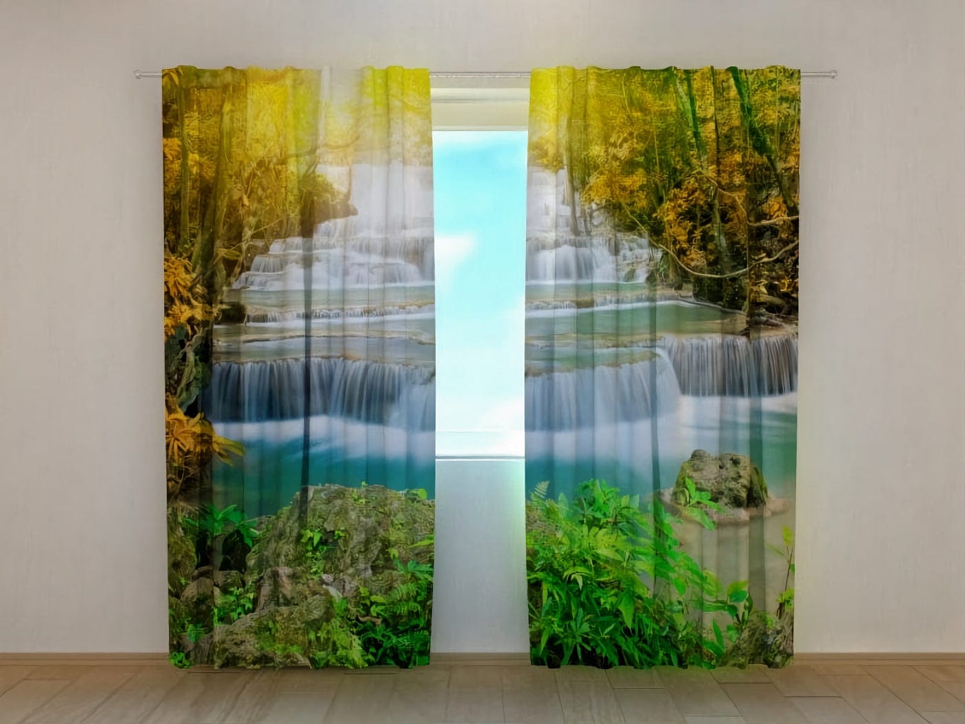 The room’s interior is unfurnished and features a wooden floor. Photo curtains are hung on the window, displaying a photorealistic depiction of a natural landscape: a picturesque, multi-tiered waterfall with turquoise water, framed in the foreground by rocks and bright green plants, while in the background—a forest with autumnal yellow and golden foliage, through which sunlight shines.