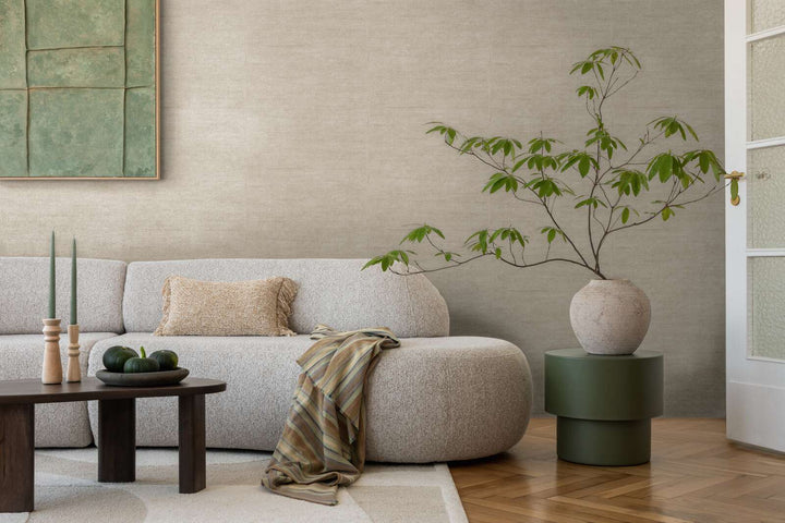 Grayish-brown textured wallpaper in a living room interior with a light sofa and natural wood parquet flooring with a light rug