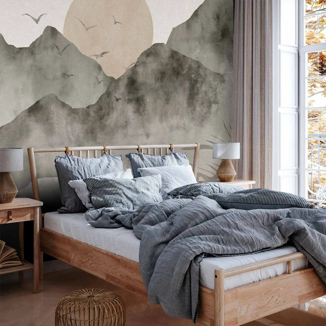 Photo wallpaper with a mountain landscape in cool tones in a bedroom interior behind a light wooden bed with grey-blue bedding and a wooden plank floor