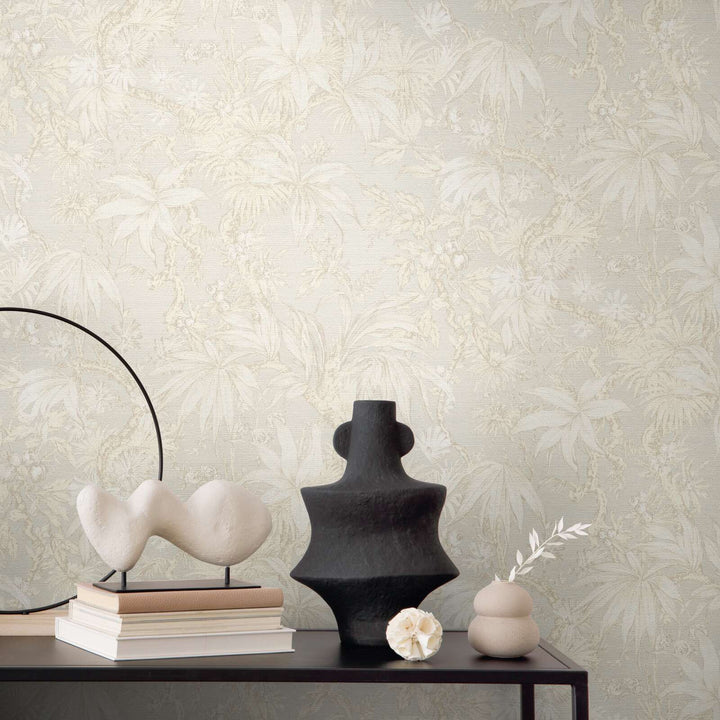 Light beige botanical pattern wallpaper in an interior behind a black table with decorative vases and sculptures