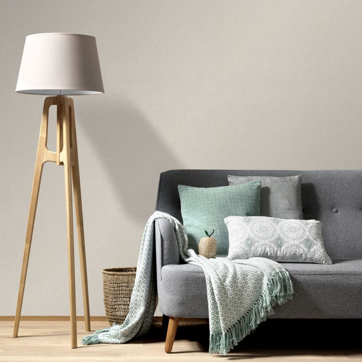Light beige textured wallpaper in a modern living room interior with a gray sofa, decorative pillows and a wooden floor lamp
