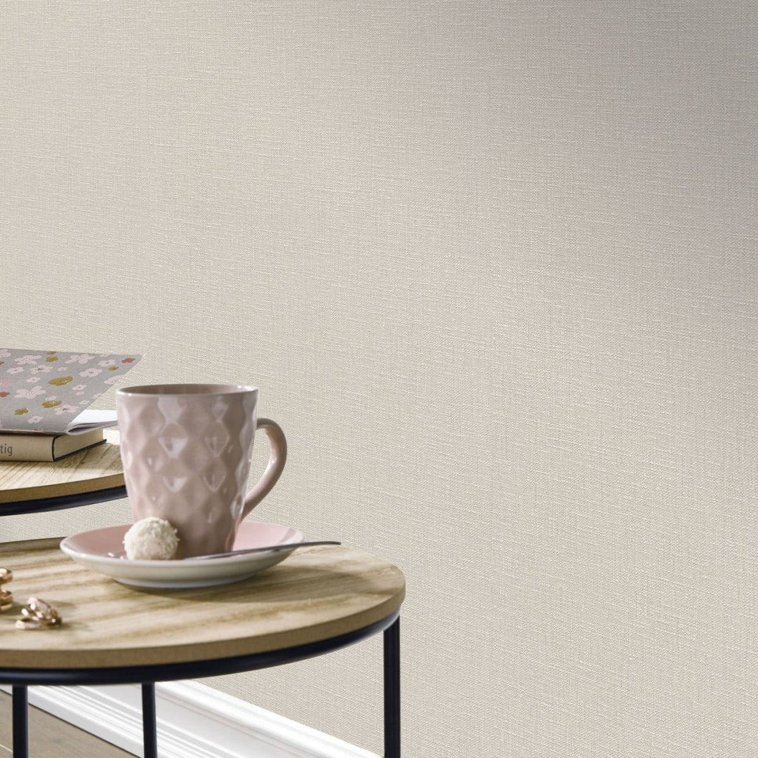 Light beige fabric imitation wallpaper in an interior with a small coffee table and a cup of coffee