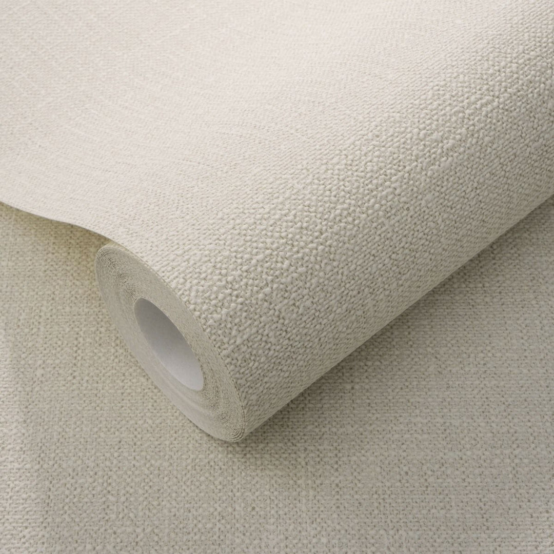 Solid light beige wallpaper roll in close-up, demonstrating a pronounced rough fabric imitation texture for wall decoration