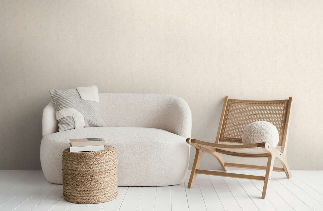 Šviesiai smėlio spalvos tapetai moderniame svetainės interjere su balta sofa, mediniu foteliu ir baltų medinių lentų grindimis