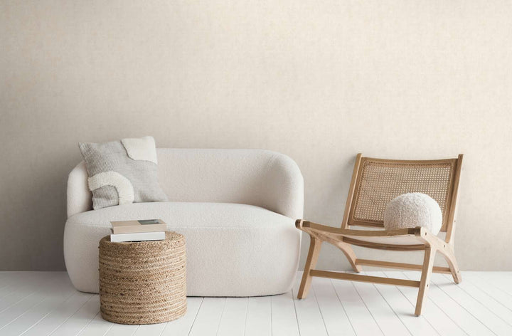 Šviesiai smėlio spalvos tapetai moderniame svetainės interjere su balta sofa, mediniu foteliu ir baltų medinių lentų grindimis