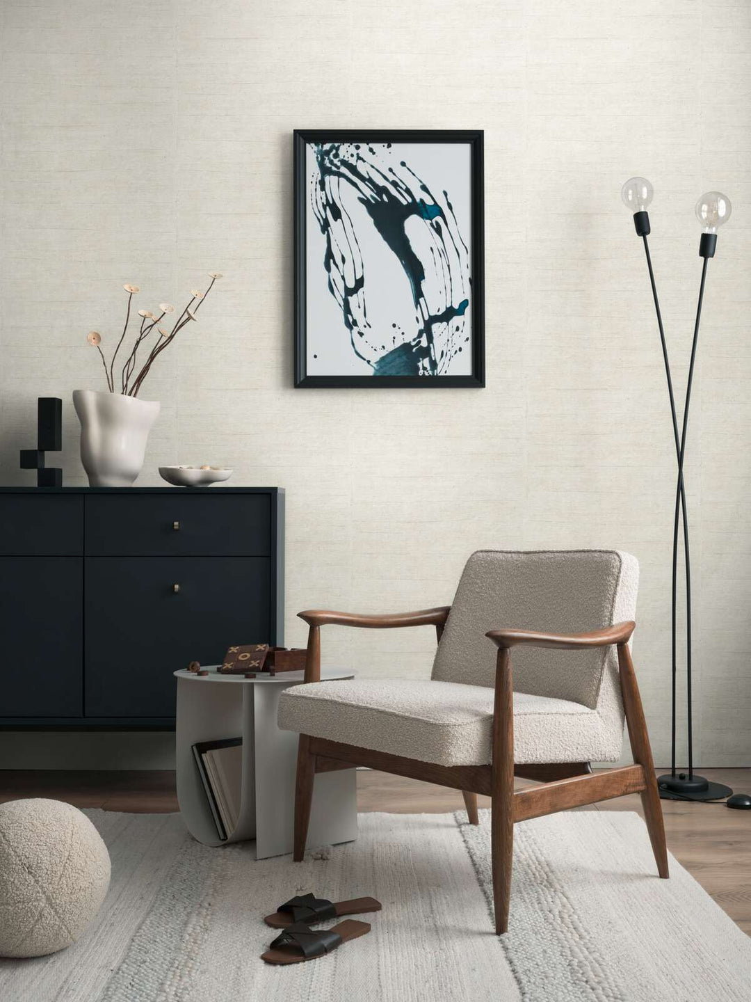 Light grayish-white textured wallpaper in an interior with an upholstered armchair, black dresser, and natural wood plank flooring with a light rug