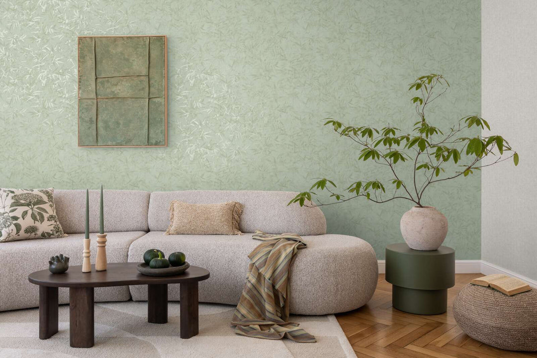 Light green bamboo leaf pattern wallpaper in a living room interior with a light sofa and natural wood parquet flooring with a light rug