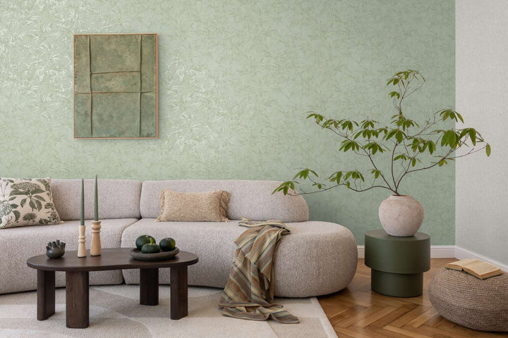 Light green bamboo leaf pattern wallpaper in a living room interior with a light sofa and natural wood parquet flooring with a light rug