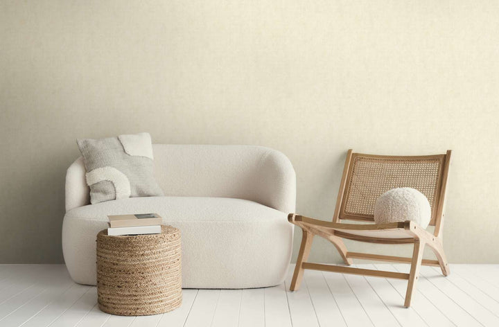 Kreminės spalvos tapetai moderniame svetainės interjere su balta sofa, mediniu foteliu ir baltų medinių lentų grindimis