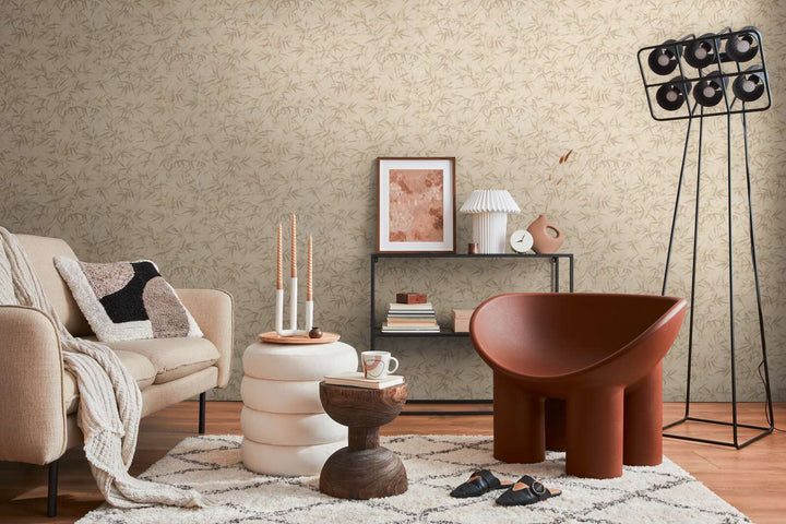 Light beige bamboo leaf pattern wallpaper in a living room interior with a light sofa, brown lounge chair, and brown wood floor with a light rug
