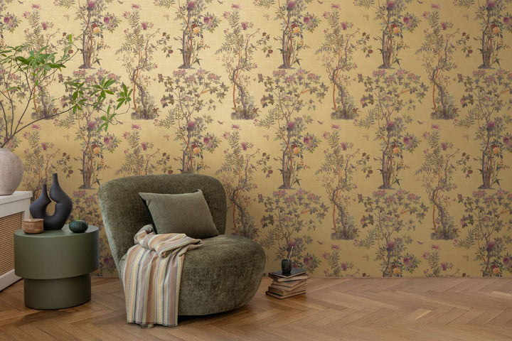 Golden-yellow illustrated nature motif wallpaper in a living room interior with a green lounge chair and natural wood parquet flooring