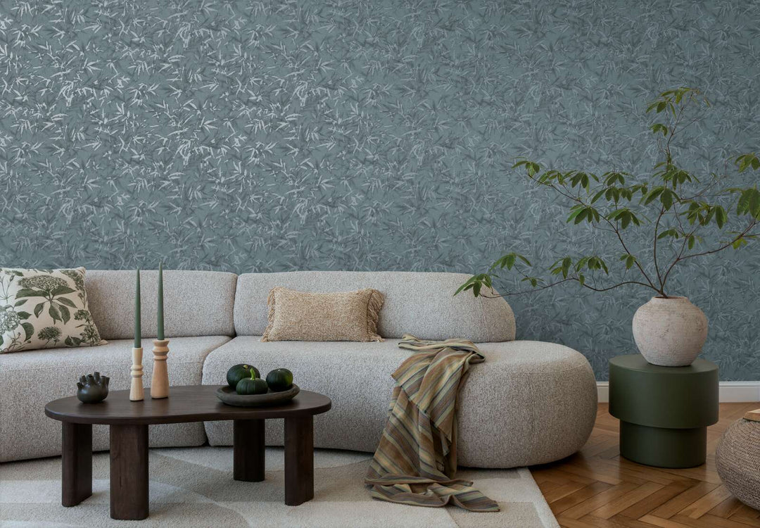 Teal bamboo leaf pattern wallpaper in a living room interior with a light sofa and natural wood parquet flooring with a light rug