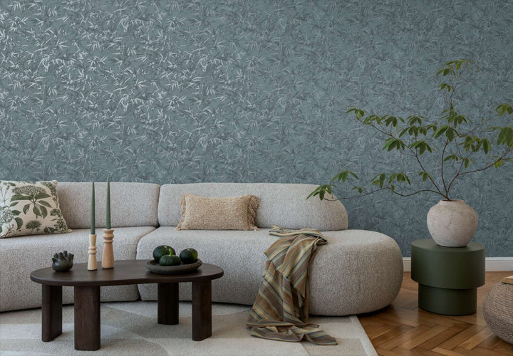 Teal bamboo leaf pattern wallpaper in a living room interior with a light sofa and natural wood parquet flooring with a light rug