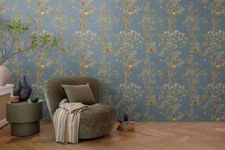 Dark blue illustrated nature motif wallpaper in a living room interior with a green lounge chair and natural wood parquet flooring