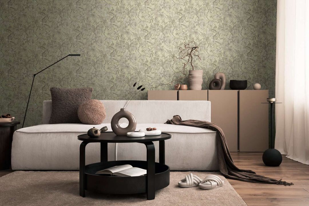 Light greenish botanical pattern wallpaper in a living room interior with a light striped sofa and brown wood plank flooring with a soft rug