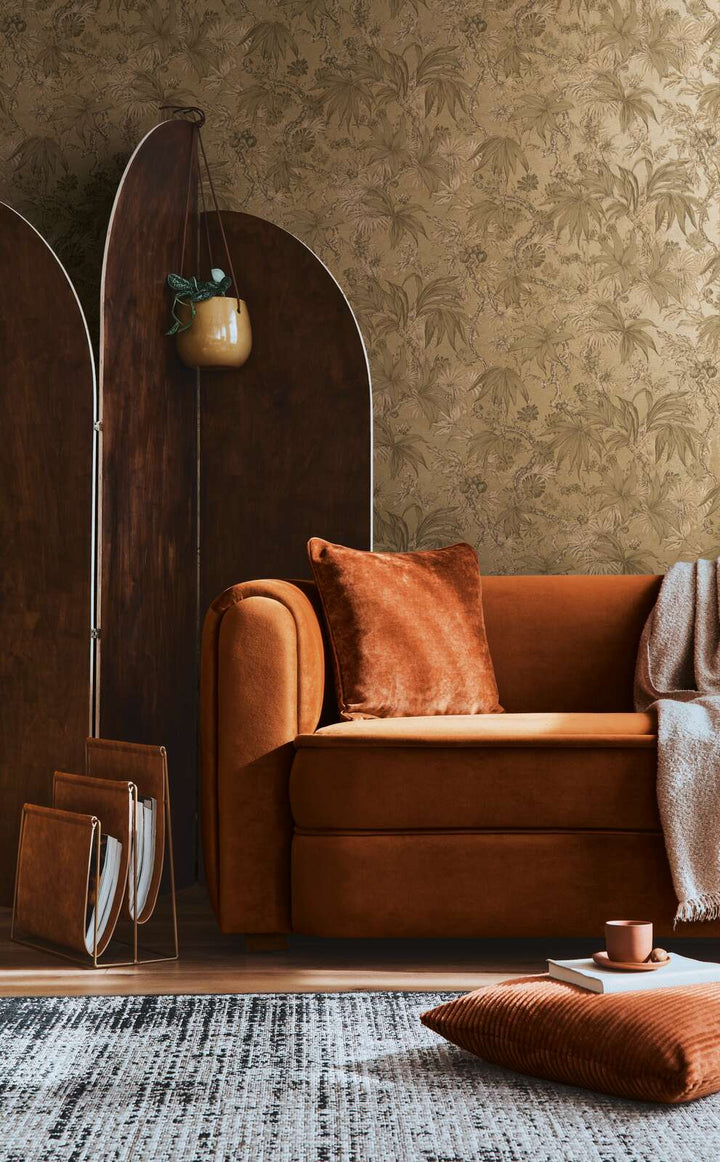 Golden-brown botanical pattern wallpaper in a living room interior with a terracotta sofa and natural wood plank flooring with a rug